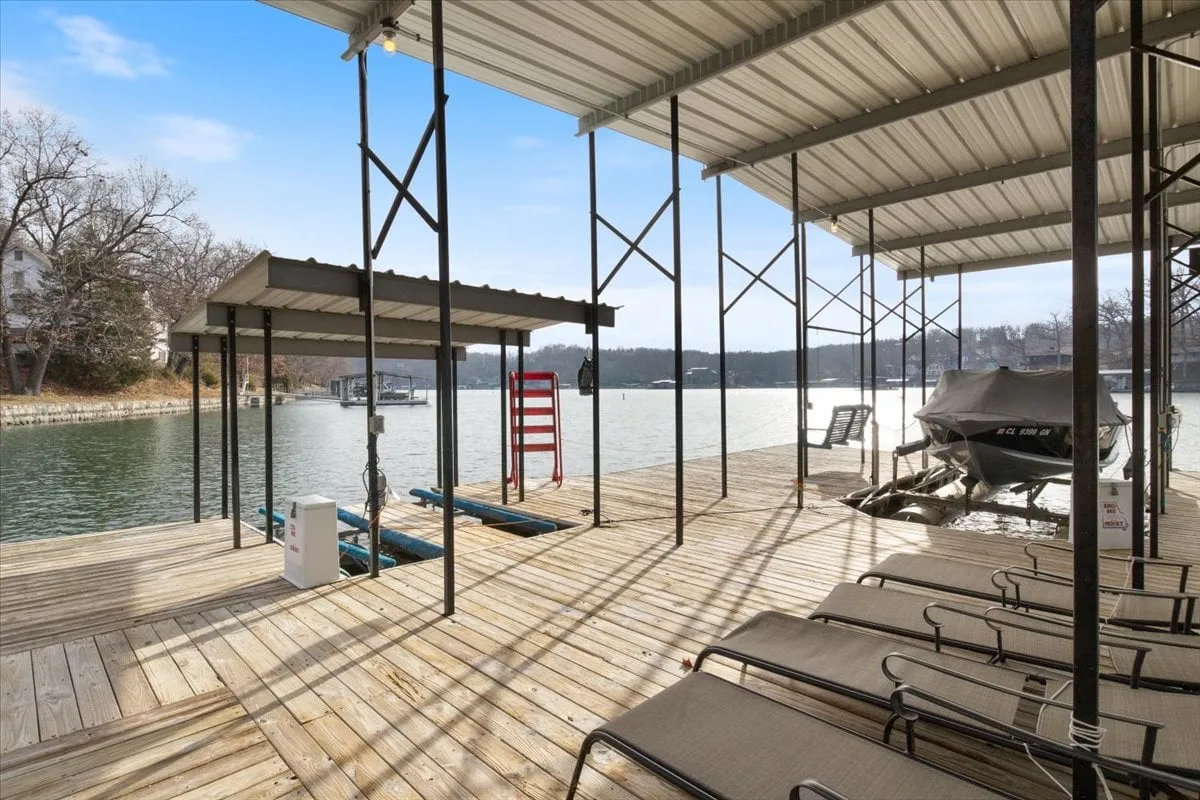 This image showcases a lakefront dock equipped with a boat lift and lounge chairs, set against a serene lake backdrop. The setting invites activities like fishing, boating, sunbathing, or simply relaxing by the water—ideal for family-friendly outdoor fun. The tranquil water and ample seating make it welcoming to all ages.