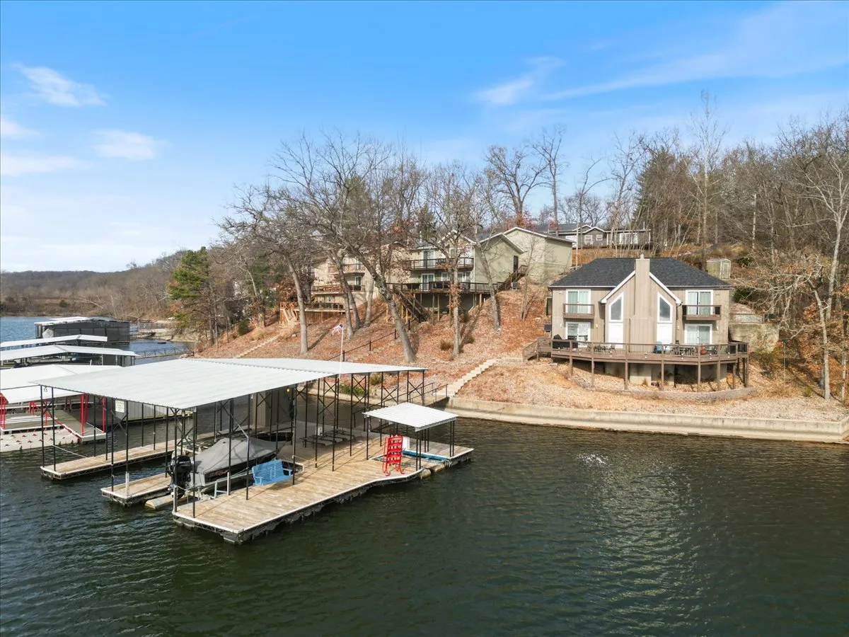 This exterior shot showcases the serene lake, the modern house, and the boat dock. The tranquil water and inviting deck highlight the peaceful lakeside setting that awaits just outside the workspace.