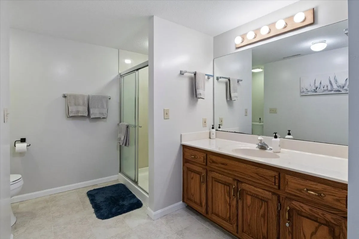 A fresh and inviting bathroom featuring a vanity with sink, a modern shower stall, and tasteful wall art. The space is well-lit, organized, and designed for comfort, offering both relaxation and convenience.