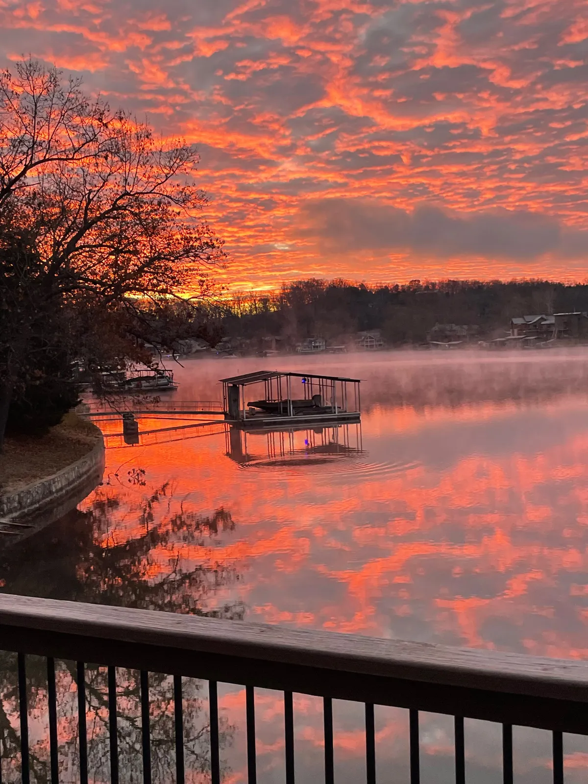 A picturesque view of the dock with a boat, set against vibrant sunset colors reflecting on the calm water. The scene feels serene and inviting, perfect for unwinding after a day of lake adventures, and evokes the tranquil moments spent watching the sunset over the water.